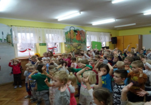 Dzieci tańczą z rękoma w górze.